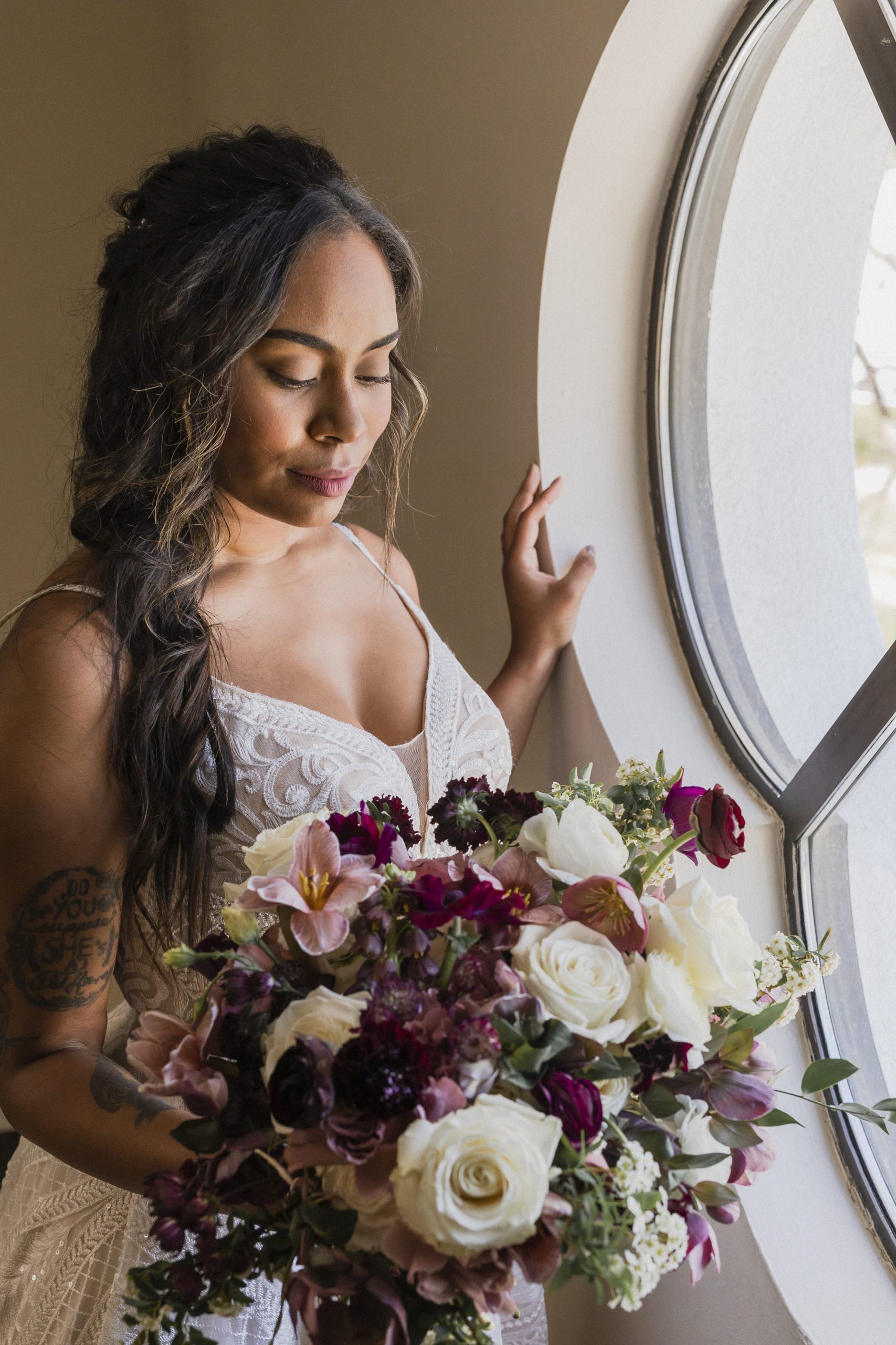 Bride with bouquet looking out the window at the Wente Event Center